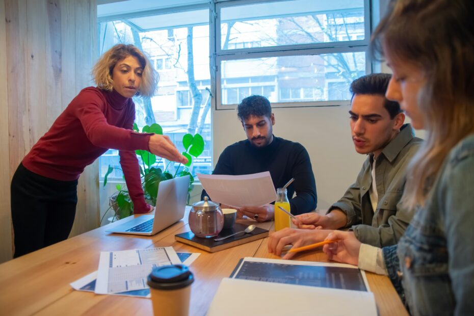 Professionals collaborating in a modern office setting with laptops and documents.
